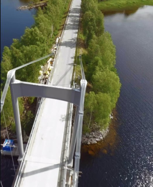 FPV drone diving past the tower of a suspension bridge over a lake